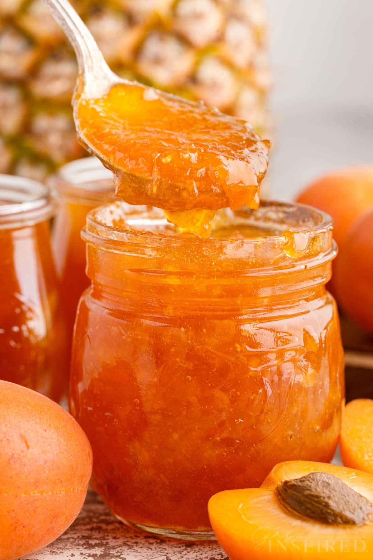 Jar of apricot pineapple jan with spoon scooping out a scoop.