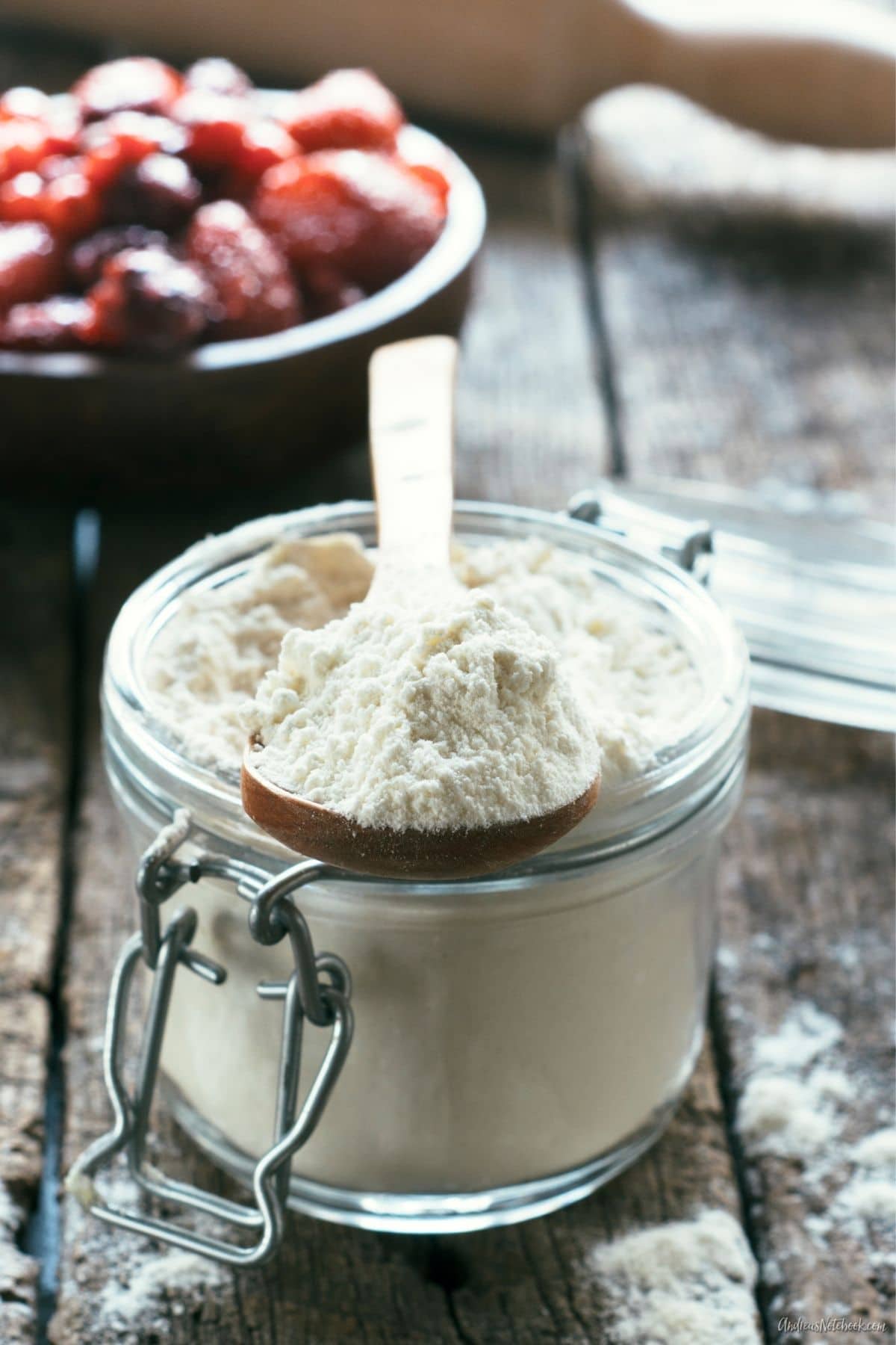 clear glass storage canning jar full of white flour mix on wood table with wood spoon on jar