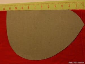 yellow cutting mat on floor. Cardboard shaped like one ladybug costume wing on top of red fabric.