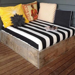 wood frame daybed on deck with black and white bedding with yellow pillows