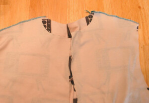 Hoodie pattern pieces laying right sides together with the should seams sewn.