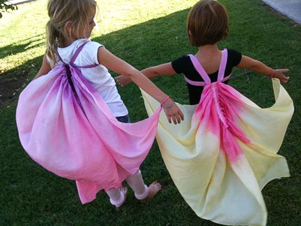 Two little girls wearing DIY silk butterfly wings that are dyed pink, yellow and putple.