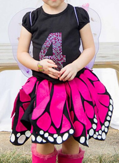 Child wearing a black t-shirt with a 4 on it and an adorable pink, black and white twirly skirt that looks like butterfly wings.