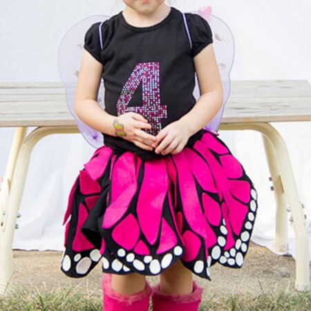 Child wearing a black t-shirt with a 4 on it and an adorable pink, black and white twirly skirt that looks like butterfly wings.