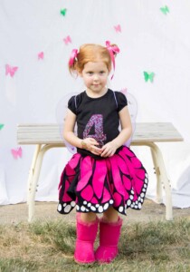 Little girl wearing a black t-shirt with a 4 on it and an adorable pink, black and white twirly skirt that looks like pink butterfly wings.