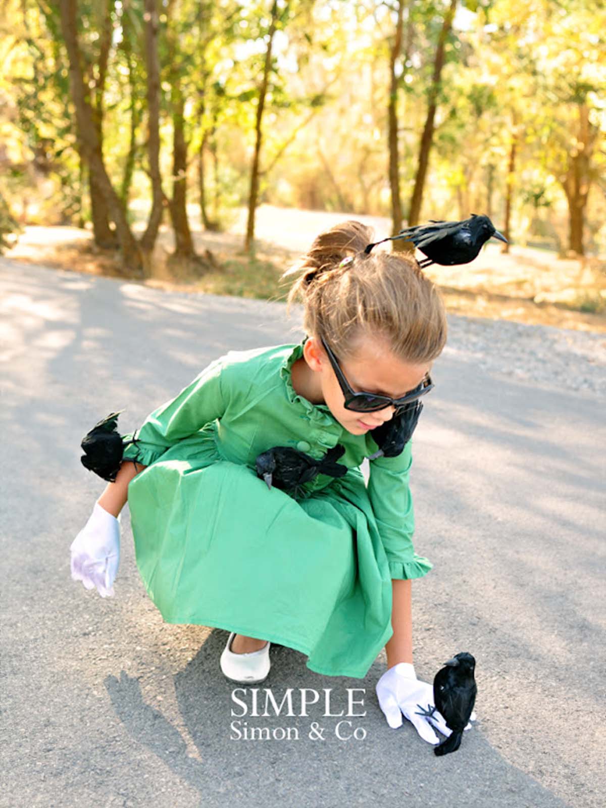 Girl in a green dress with fake black birds on her for a "The Birds" costume.