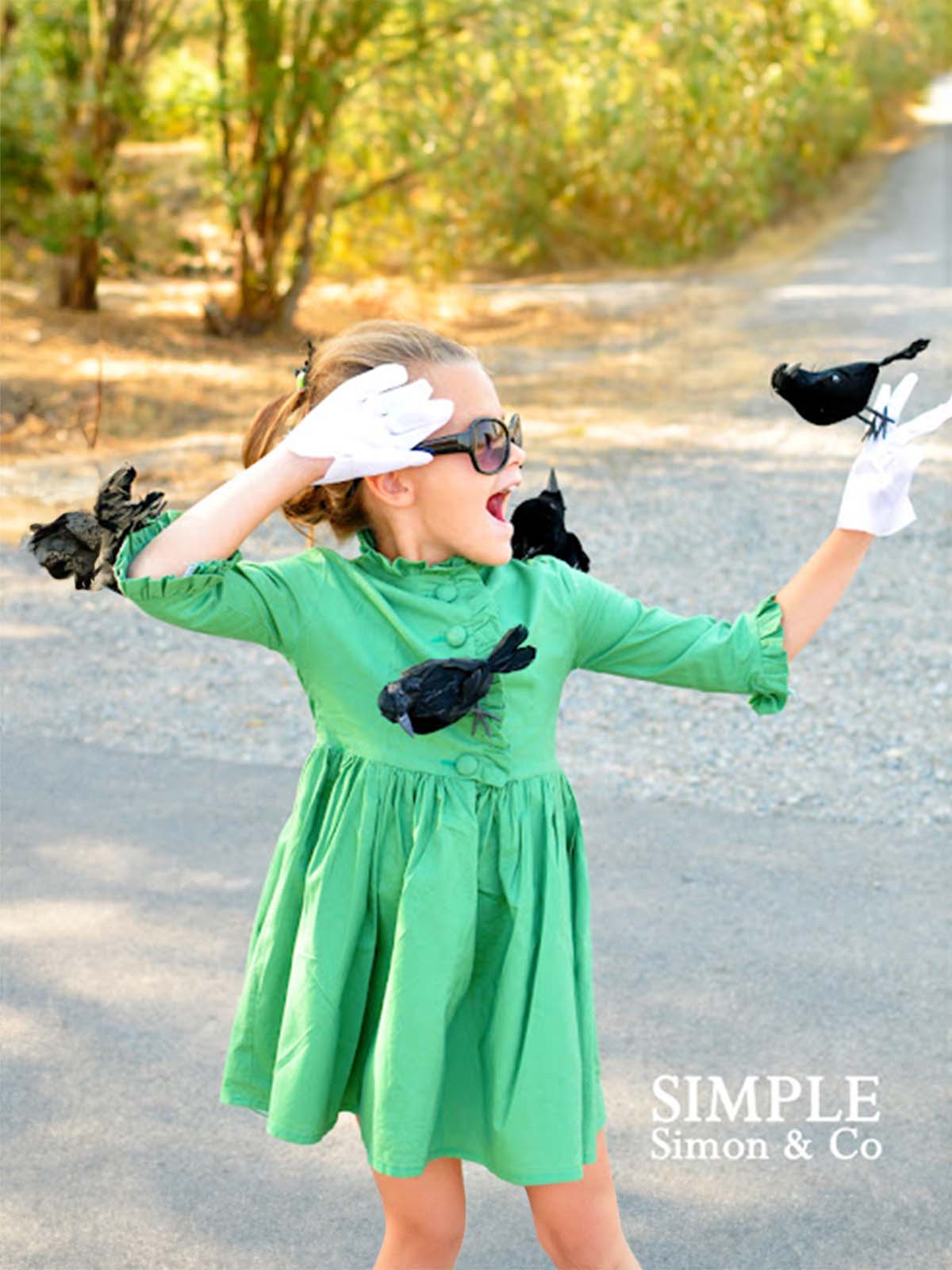 Girl in a green dress with fake black birds on her for a "The Birds" costume.