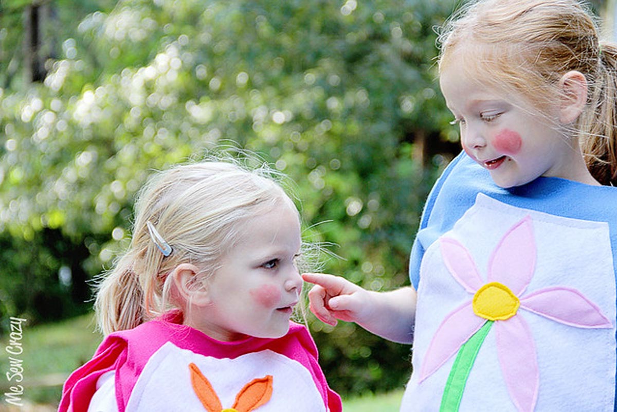 Two girls, one pointing at the red dot of blush on another's cheek.