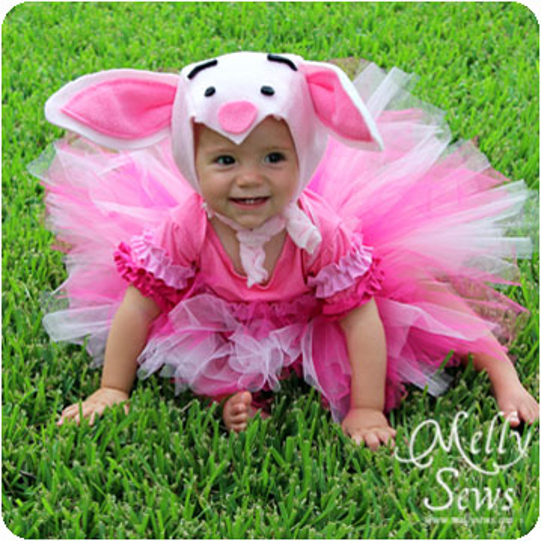 Little girl wearing tutu and piglet hat.