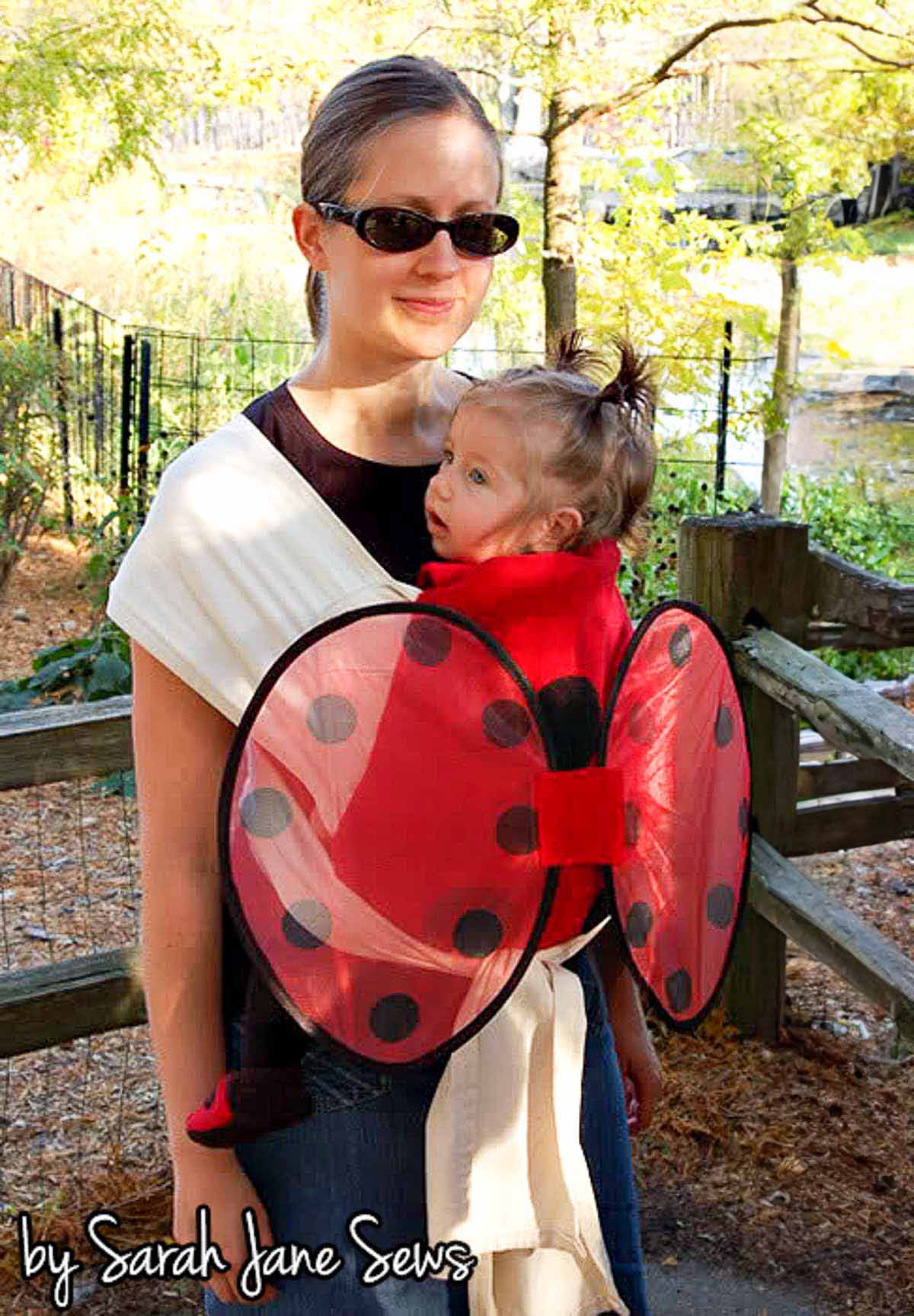 Woman wearing a baby in a baby carrier that is a DIY ladybug costume.