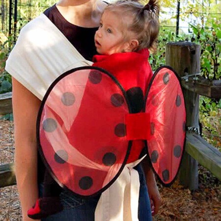 Homemade ladybug carrier cover on a baby in a carrier being worn by her mother.