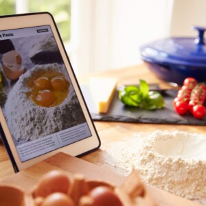 Recipe on a tablet on a kitchen counter with cooking ingredients.