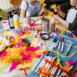 Messy table full of paint, markers, feathers, eggs and messy art projects for kids.