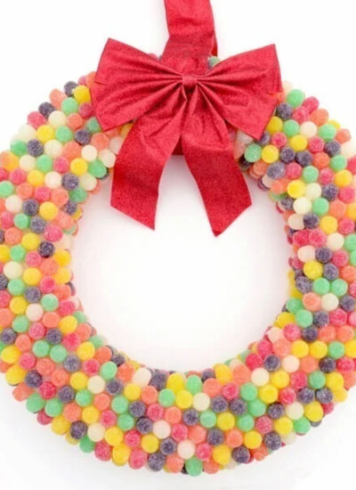 Colorful DIY gumdrop wreath with a red bow on top.
