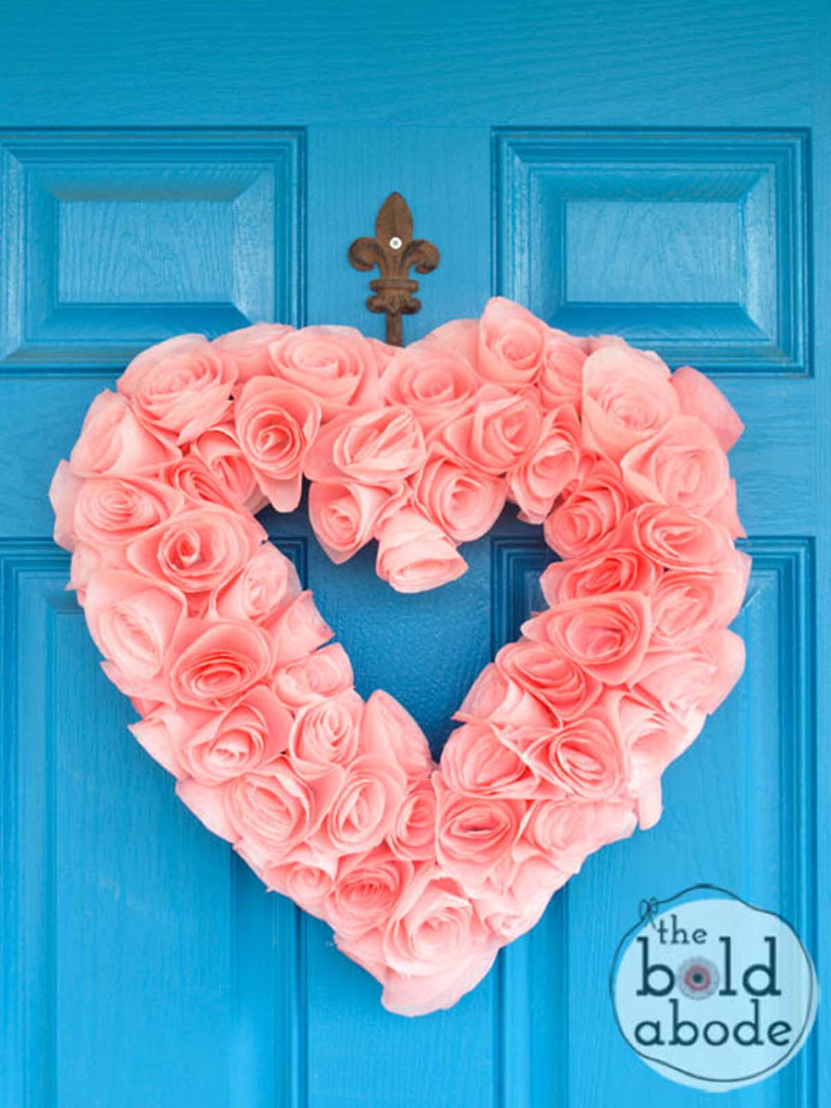 Pink DIY Valentine's Day coffee filter heart wreath on a blue front door.