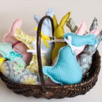 Basket with a handle full of simple stuffed bunny pillows with ribbon bows on their necks.