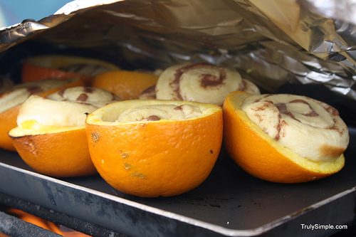 Bake a cinnamon roll in an orange over a campfire