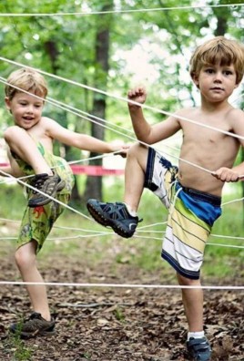 shirtless little preschool boys navigating ropes obstacle course
