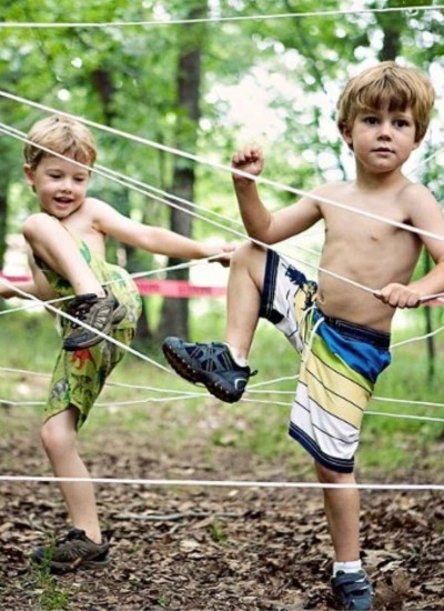 shirtless little preschool boys navigating ropes obstacle course