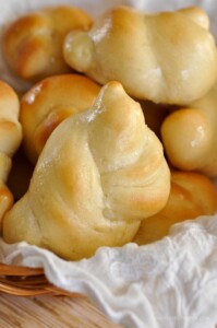Basket full of golden knotted yeast dinner rolls made with lion house rolls dough.