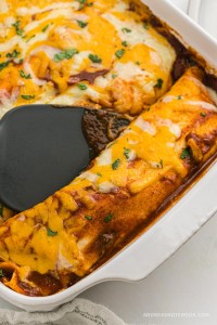 Homemade chicken enchiladas with red sauce in a casserole dish.