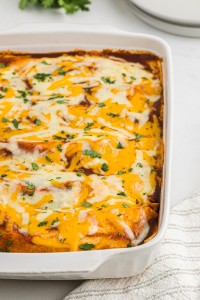 Homemade chicken enchiladas with red sauce in a casserole dish.