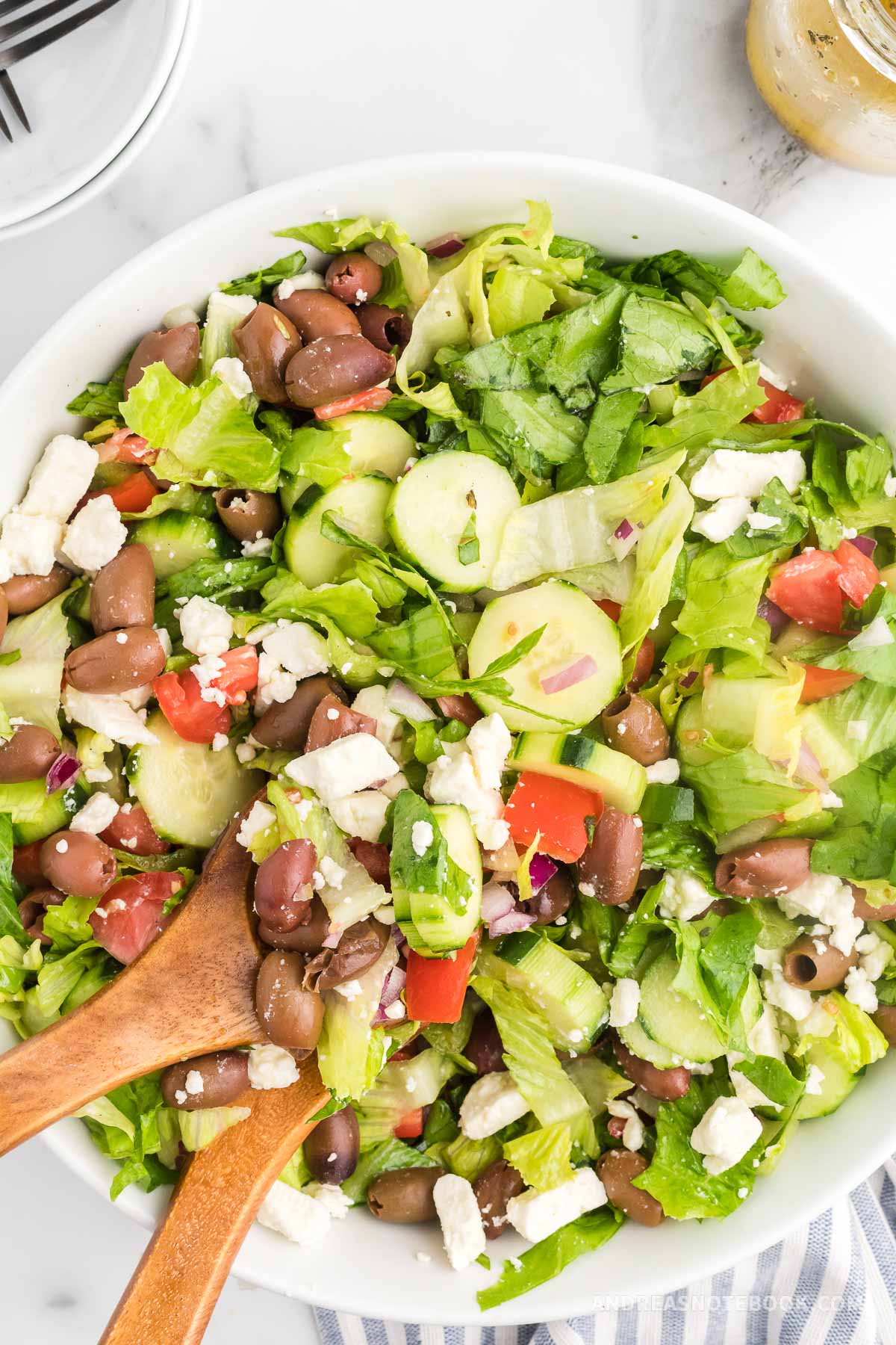 Greek salad with tomatoes, kalamata olives, cucumber, feta cheese and red onions in a large bowl.