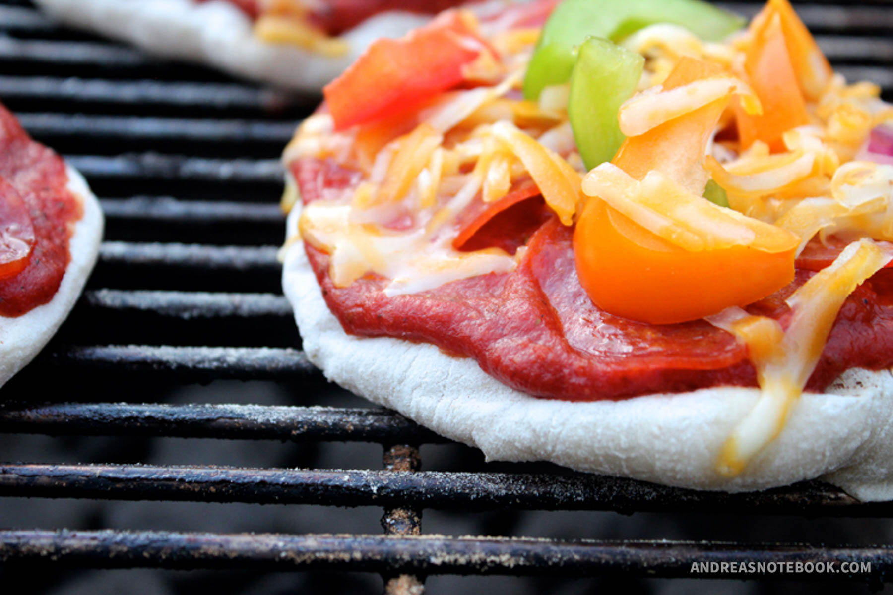Pizza on the grill with fresh toppings on top.
