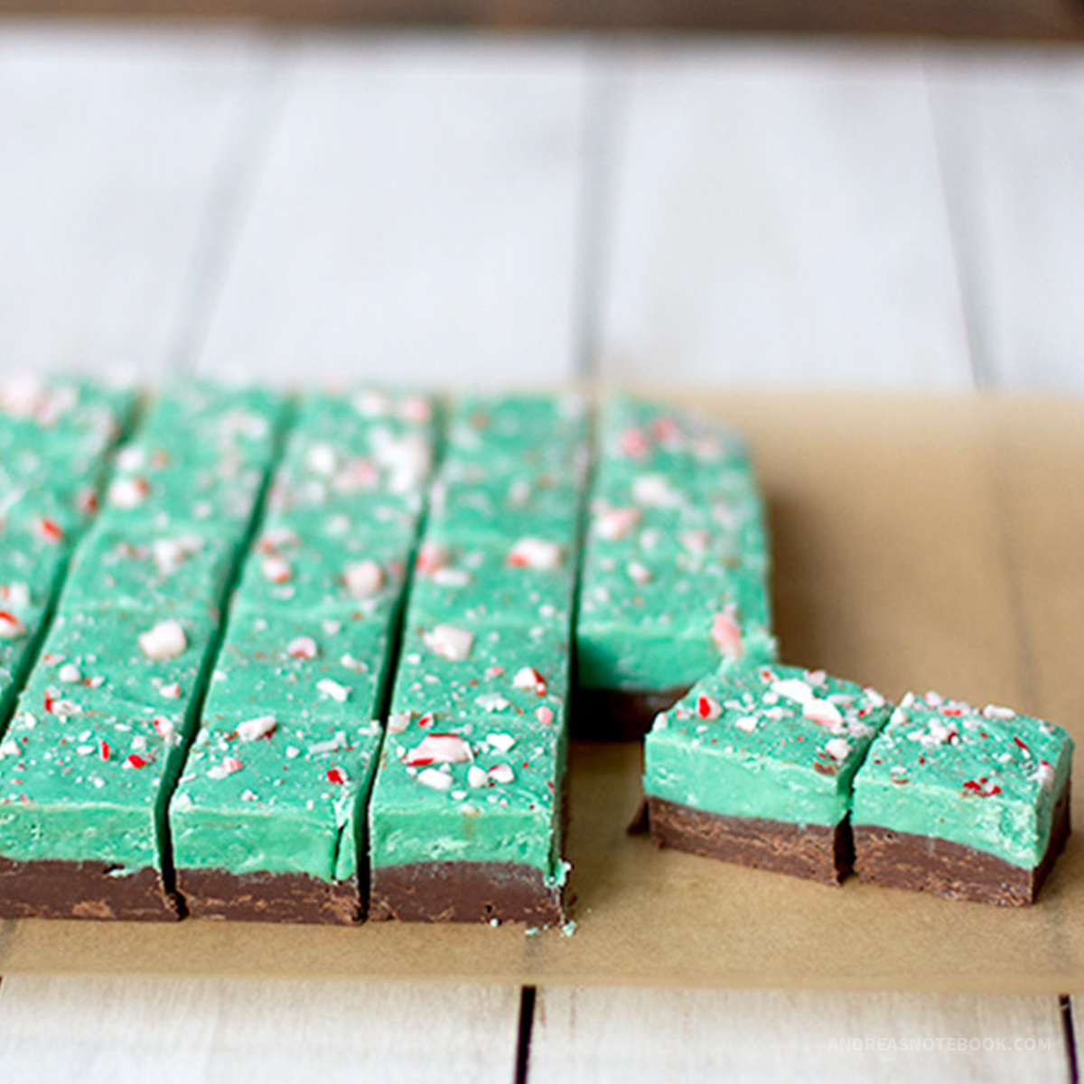 Squares of green and mint chocolate christmas fudge on parchment paper.