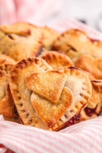 Golden heart shaped cherry hand pies in a basket.