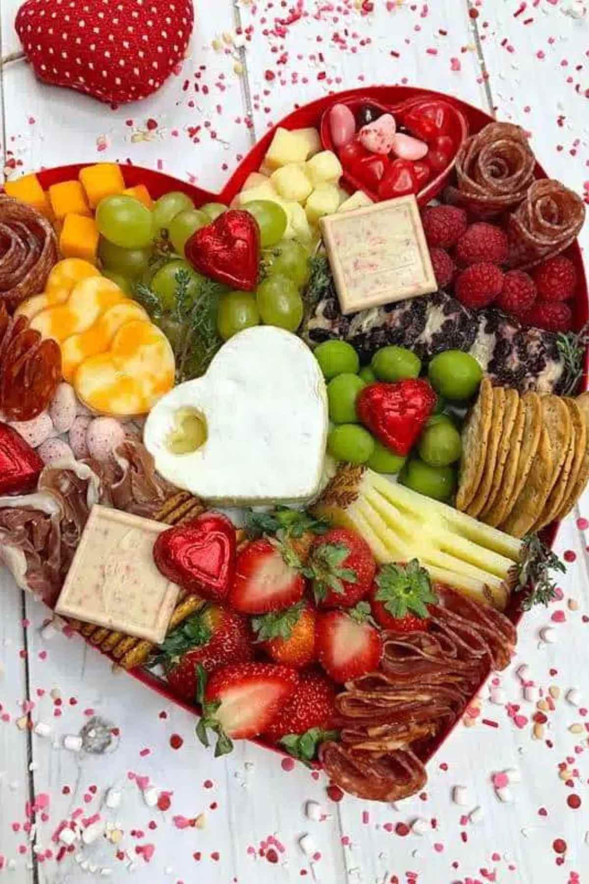 Heart shaped charcuterie board with fruit, cheese and crackers.