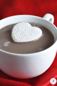 Homemade heart-shaped marshmallow in a white mug of hot cocoa.