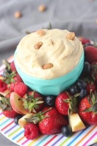 Bowl of peanut butter cream cheese fruit dip surrounded by a plate of fruit.
