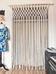 White DIY macrame curtain over a doorway by A Beautiful Mess.