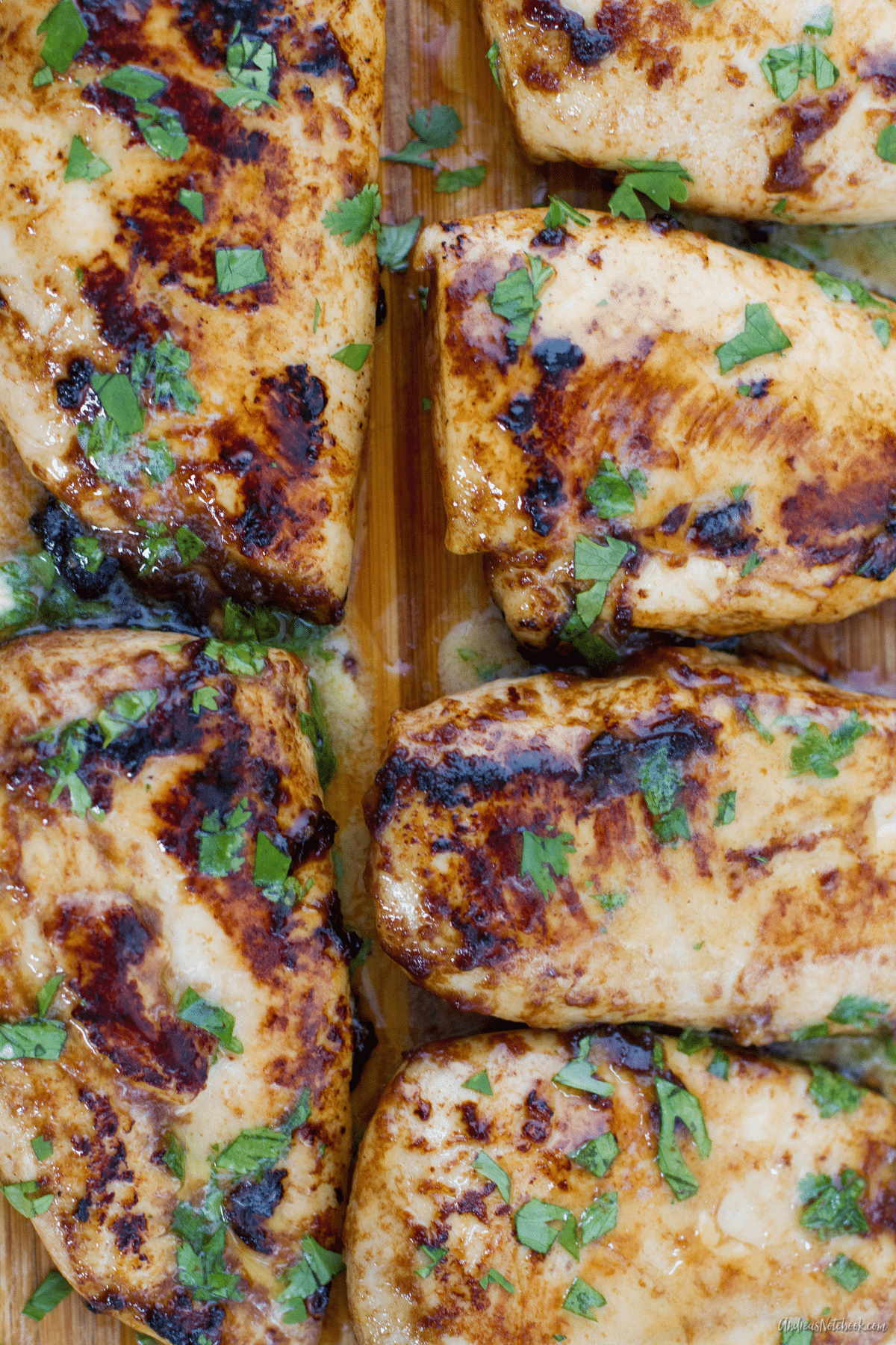 juicy cooked chicken breasts on a cutting board with cilantro on top