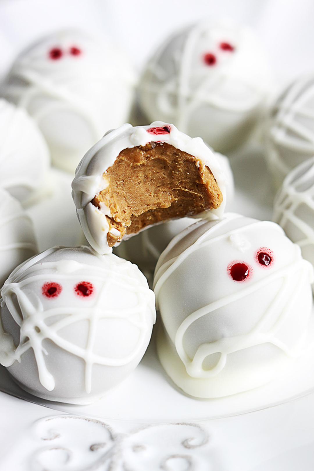 White pumpkin cheesecake truffles decorated like mummies.