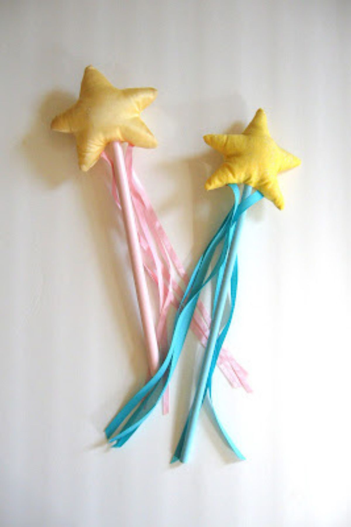 Two homemade fairy wants, one pink and one blue with yellow padded stars on top.