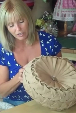 woman holds brown round pillow