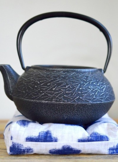 black cast iron teapot on white and blue tea trivet