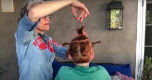 woman gives son haircut while his hair is in little ponytails
