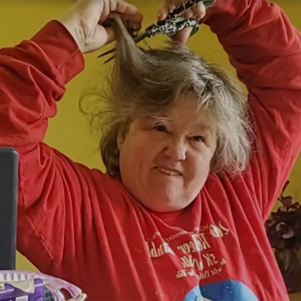 woman makes funny face while cutting her hair