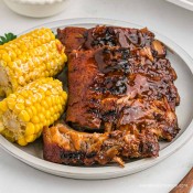 Plate full of corn on the cob and baby back ribs.