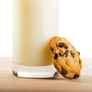 one cookie leaning against a glass of milk