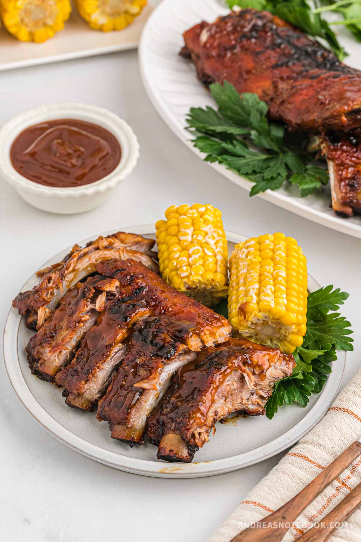 Plate full of barbecue ribs and corn on the cob.