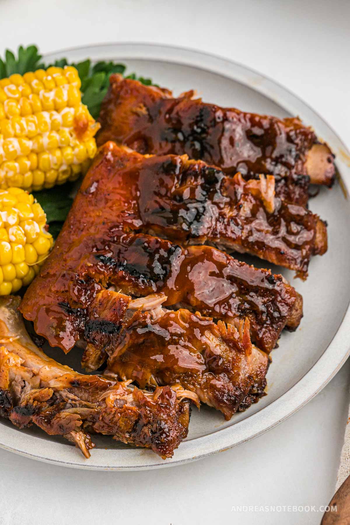 Plate full of oven baked baby back ribs with a dry rub and bbq sauce on a plate.
