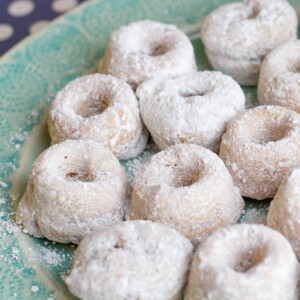 Plate full of powdered sugar mini gluten-free baked donuts.