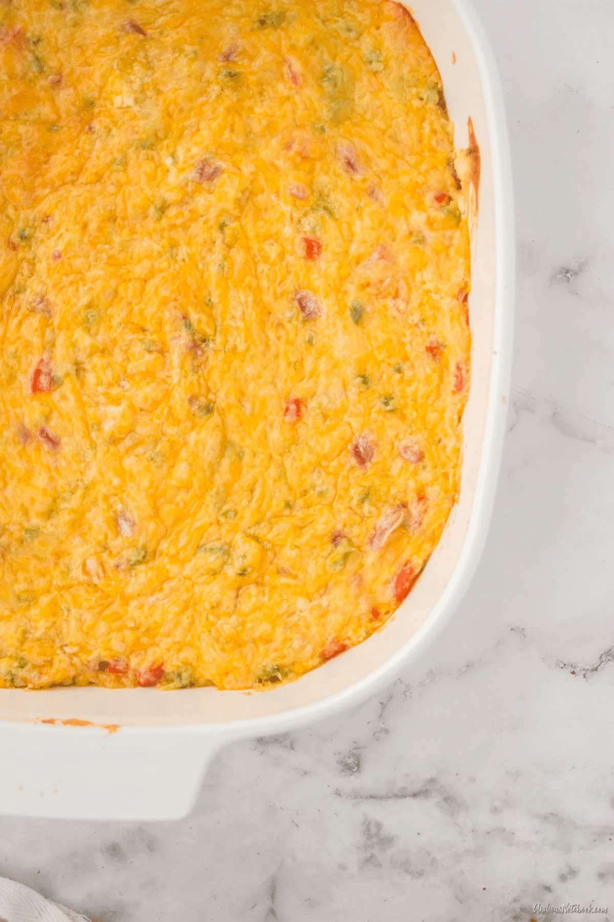cheesy jalapeño dip in a rectangular white casserole dish on a marble counter
