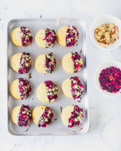 Cookie sheet of cooked chocolate dipped shortbread cookies sprinkled with rose petals.