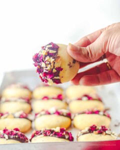 Hand holding up one rose shortbread cookie.