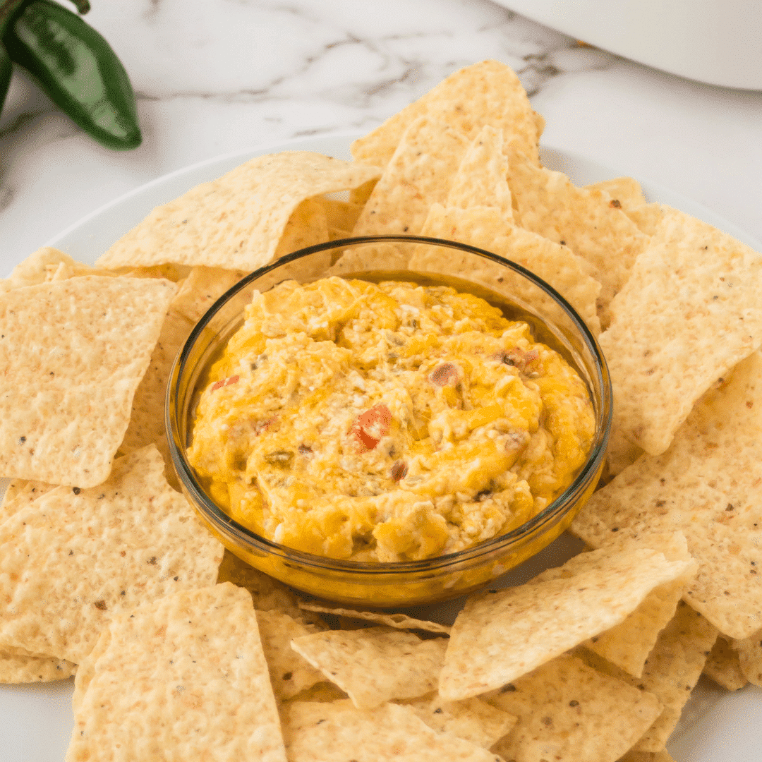 cheesy jalapeño dip in a bowl surrounded by tortilla chips